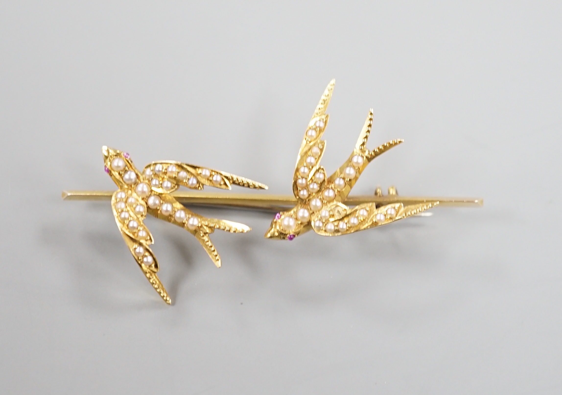 An Edwardian yellow metal and seed pearl set twin swallow bar brooch, 54mm, gross weight 6.5 grams.